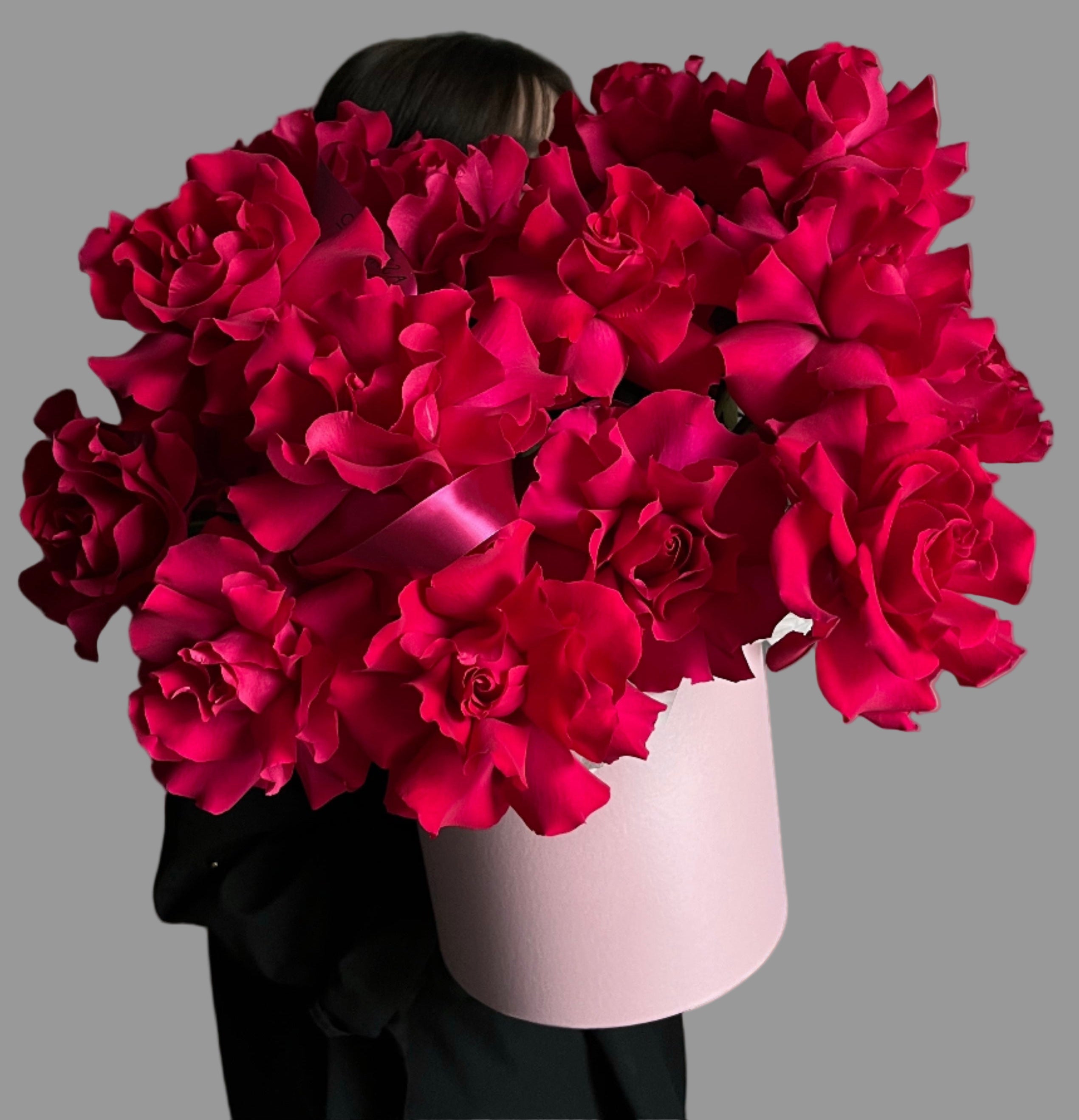 Person holding a large bouquet of red flowers against a white background